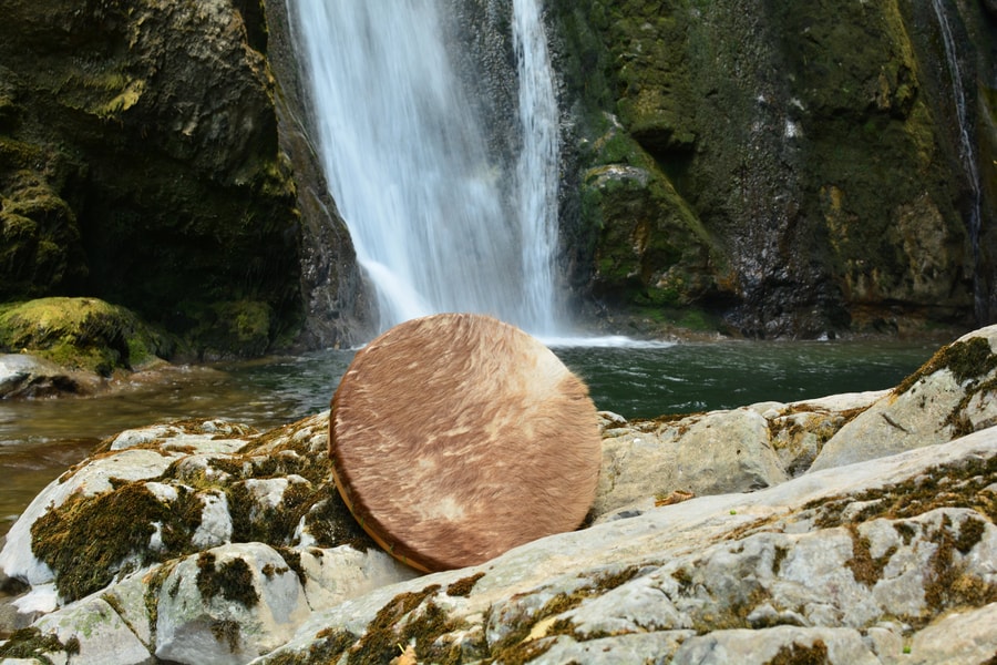 Tambour de soin chamanique près d'une cascade